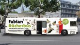 Een bus met het opschrift "Bücherbus Fabian" staat of rijdt op straat in de stad