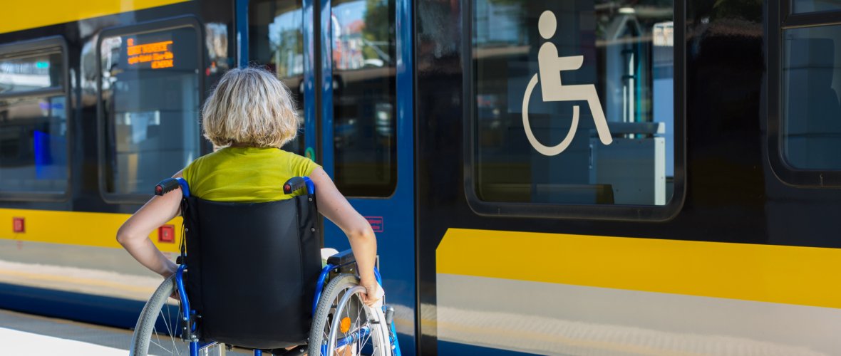 Een vrouw zit in een rolstoel op het perron.