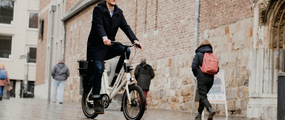 Persoon rijdt op een e-bike vanaf een deelstation door het stadscentrum