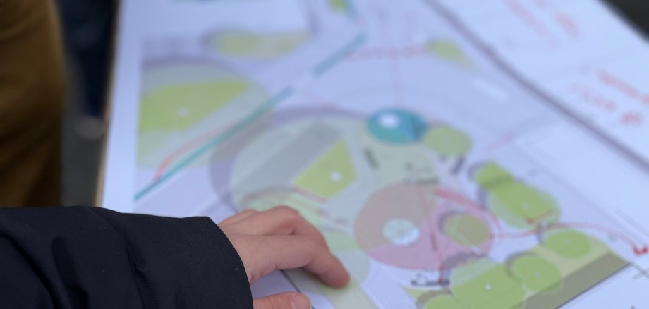 Een hand wijst naar een plattegrond van de herinrichting van de Klappergasse en de Rennbahn in Aken