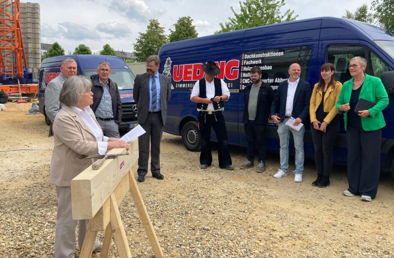 Mevrouw Hajok, hoofd van de afdeling Bouw, verwelkomt de gasten bij de topping-out ceremonie.