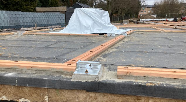 De egalisatiebalken aan de onderkant van de houten constructiemuren worden geïnstalleerd.