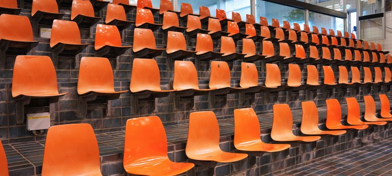 De tribune bestaat uit 5 rijen stoelen. Het zijn oranje plastic kuipstoelen.
