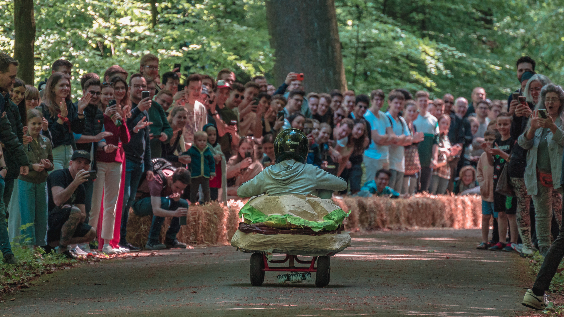 Op één route rijdt iemand in een zeepkist de Lousberg af langs een menigte mensen.
