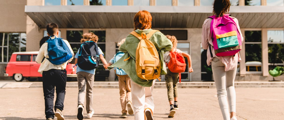 Groep schoolkinderen rent haastig naar het schoolgebouw .