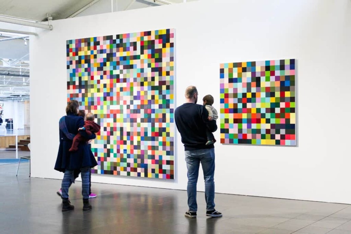 Ouders met een kind in hun armen staan in het museum en kijken naar een kunstwerk.