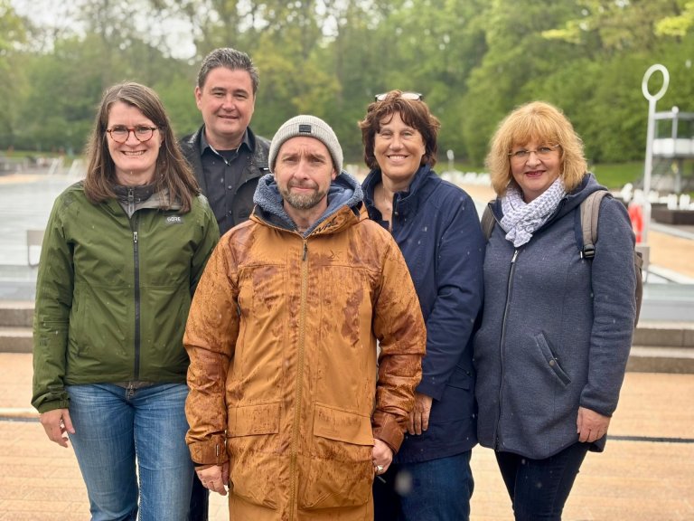 Een groep van vijf mensen - vier vrouwen en een man - staat voor het overdekte zwembad van het buitenbad.