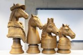 4 gouden, oversized schaakstukken waarop paardenhoofden met verschillende versieringen en ornamenten zijn afgebeeld.