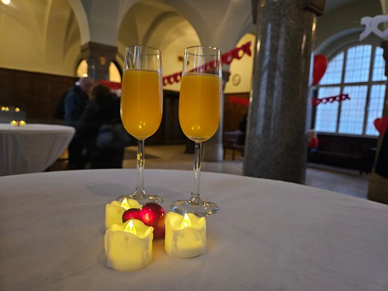 Twee champagneglazen met sinaasappelsap en kaarsen