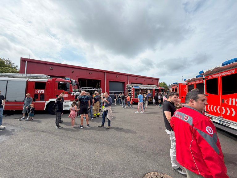 Een brandweerkazerne met hulpverleningsvoertuigen en mensen op het voorplein