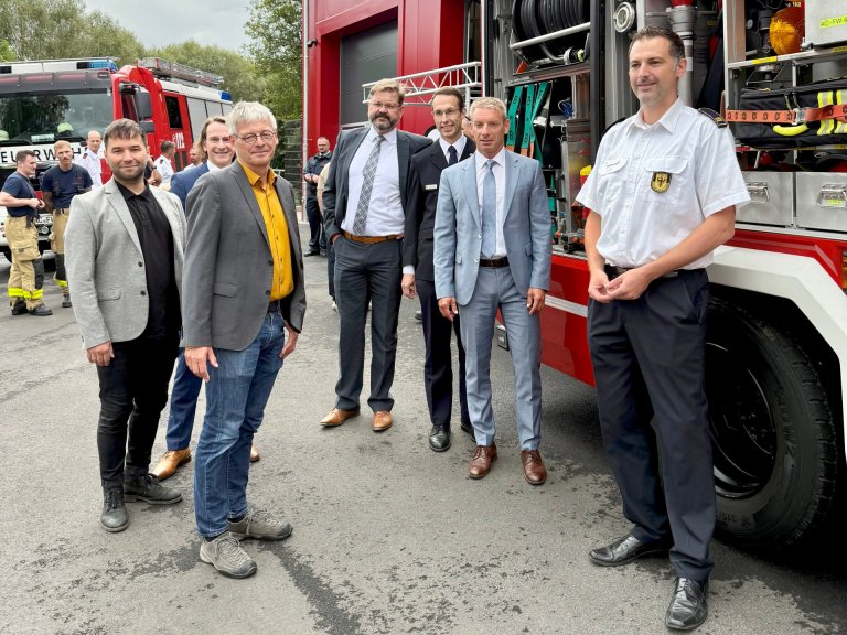 Een groep mensen voor een brandweerauto.