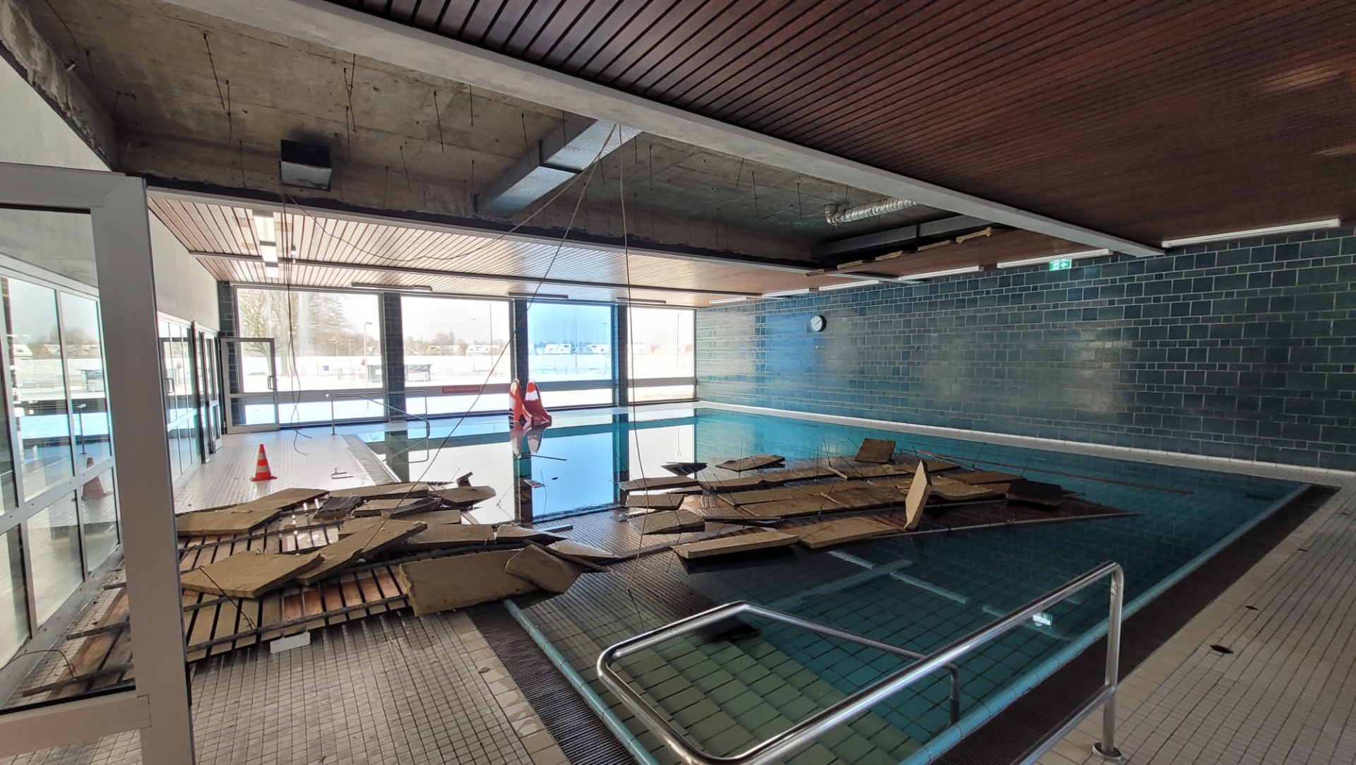 Houten delen van de plafondbetimmering liggen in een zwembad.