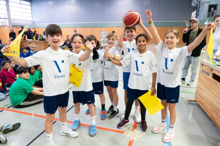Kinderen van het "die Korbjäger" team vieren hun overwinning met een trofee