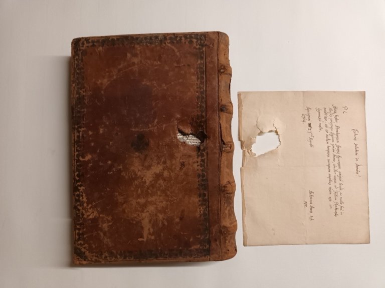 Een historisch boek met zichtbare gebruikssporen en beschadigingen