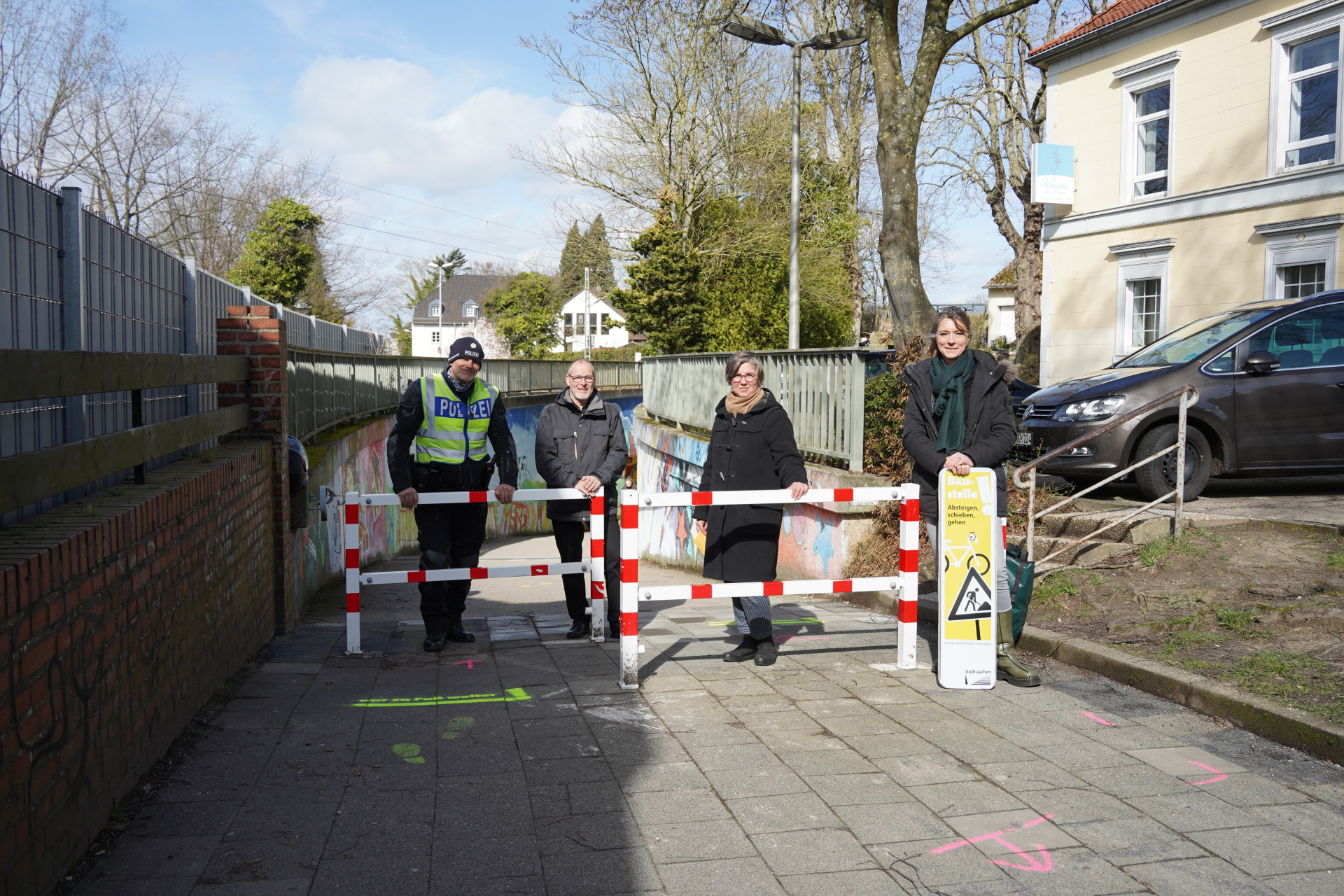 Een groep mensen staat voor een metro bij twee rood-witte barricades die bedoeld zijn om fietsers aan te moedigen af te stappen.