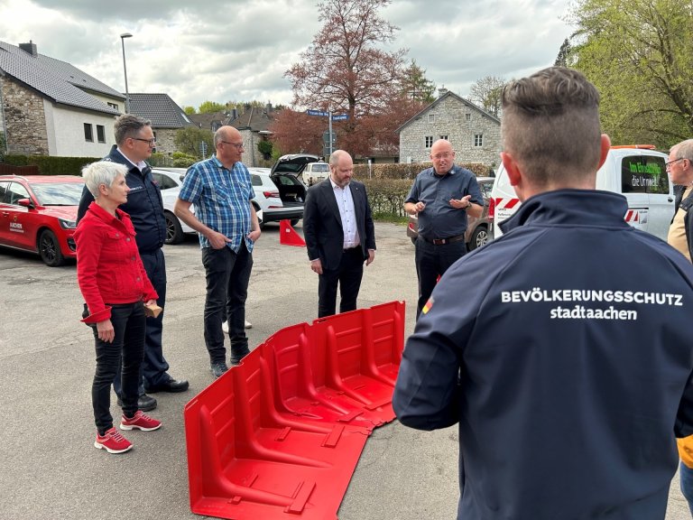 Een groep mensen staat bij elkaar op een plein, waaronder de burgemeester. In het midden staat een modulair overstromingsbeschermingssysteem.
