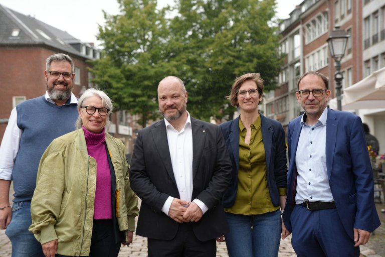 Vijf mensen op straat, een boom op de achtergrond