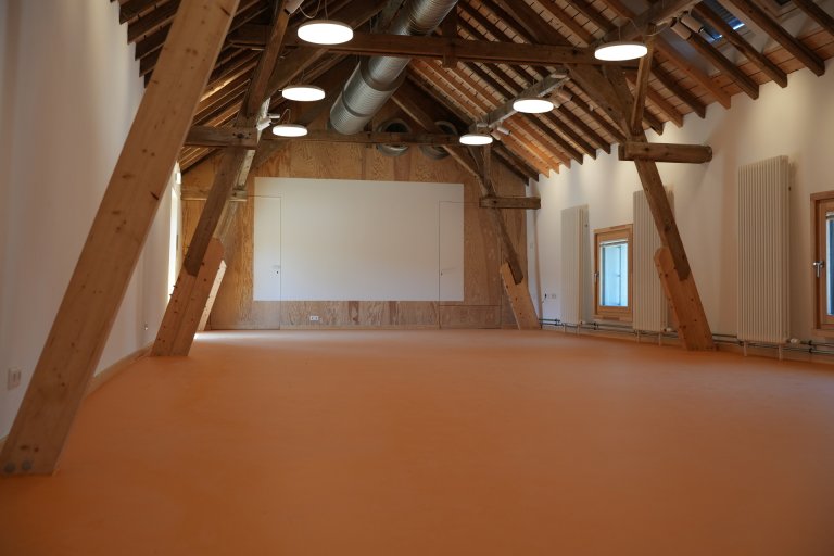 Gerenoveerde kamer met houten vloer, houten balken en witte muren.