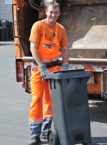 Müllwerker zieht Restmülltonne zum Müllfahrzeug