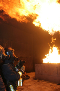Feuerwehrmann in Schutzkleidung vor großer Flamme