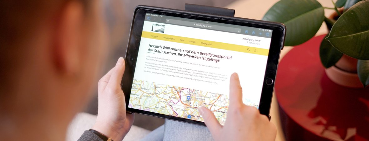 Eine Frau bedient ein iPad auf dem die Seite des Beteiligungsportals geöffnet ist.