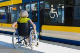 Frau sitzt in einem Rollstuhl am Bahnsteig.