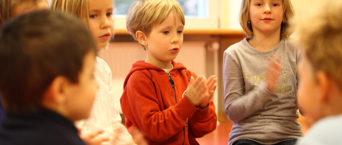 Kinder sitzen im Kreis und klatschen