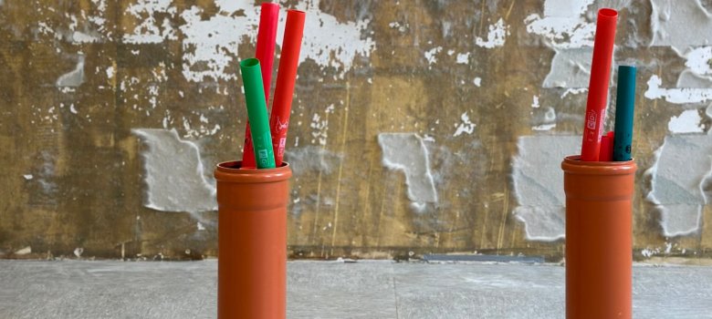 In zwei Eimern stehen Boomwhackers vor einer zu renovierenden Wand.