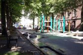 Lindenplatz in Aachen mit offener Bachrinne und Spielplatz mit Klettergerüst im Hintergrund.