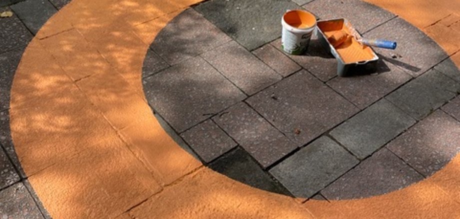 Ein gemalter orangefarbener Ring auf dem Boden.  