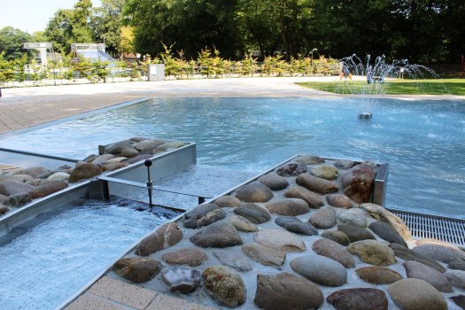 Das Ende des Bachlaufs mit Schleuse und der flachen Spielwasserfläche mit Springbrunnen für Kinder.