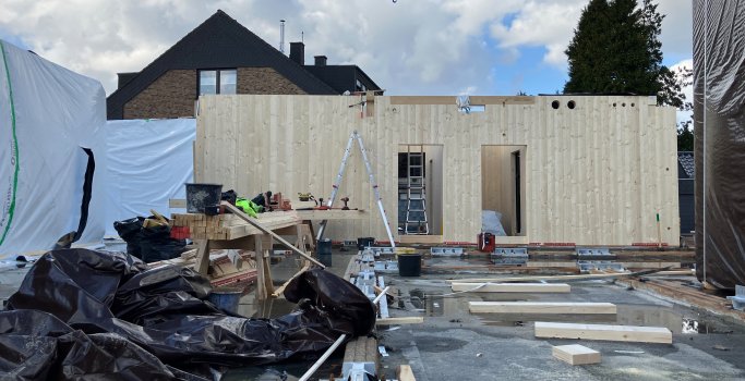 Die Arbeiten an den Holzbauwänden schreiten voran. Zu sehen ist auch der Regenschutz für die bereits erstellten Holzelemente.