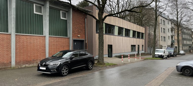 Die Straßenperspektive zeigt die Holzfassade des Erweiterungsbaus.