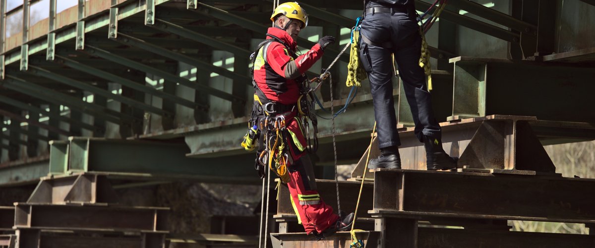 Ein Brandmeister-Anwärter wird durch einen Höhenretter an einer stählernen Gittermast-Struktur in Absturzsicherung ausgebildet. Die Übung wurde am Falkenbach-Viadukt durchgeführt.