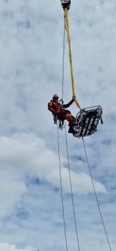 Vorbereitung der Rettung einer adipösen Person mittels Feuerwehrkran und Schleifkorbtrage. Der Retter hängt neben der Trage um den Patienten im weiteren Einsatzverlauf zu begleiten.