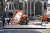 Bagger und Lastwagen verteilen bergeweise Sand in einem riesigen Sandkasten auf dem Aachener Katschhof. Im Hintergrund der Aachener Dom und blauer Himmel.