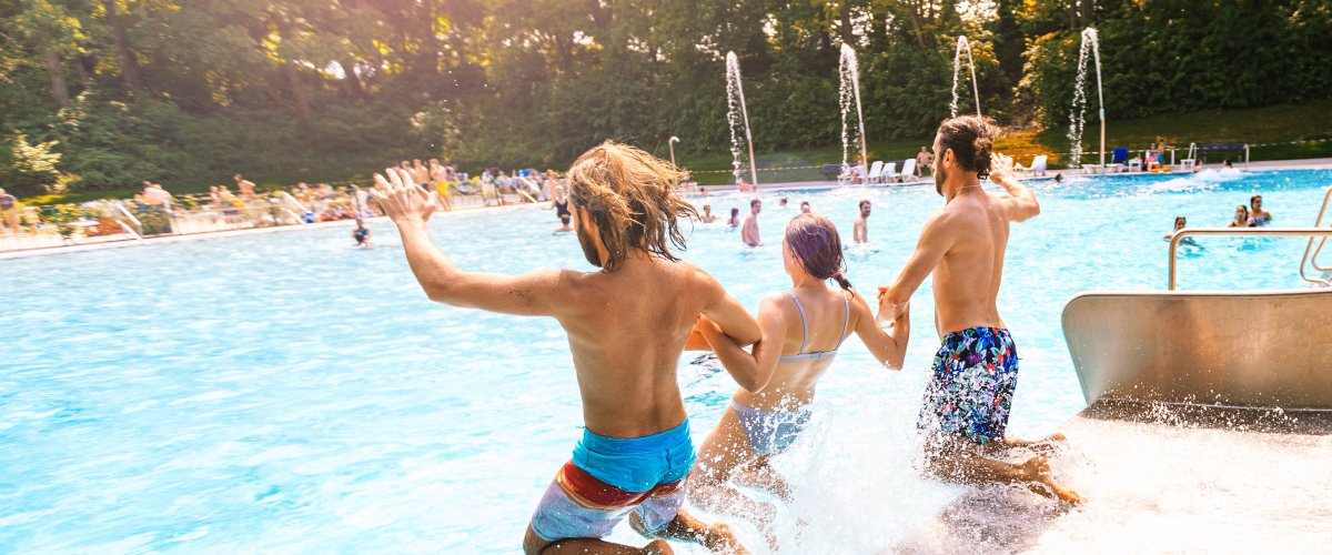 Freibad Hangeweiher Drei Freunde rutschen gemeinsam in das Schwimmbecken