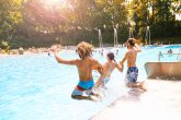 Drei Freunde rutschen gemeinsam in das Schwimmbecken