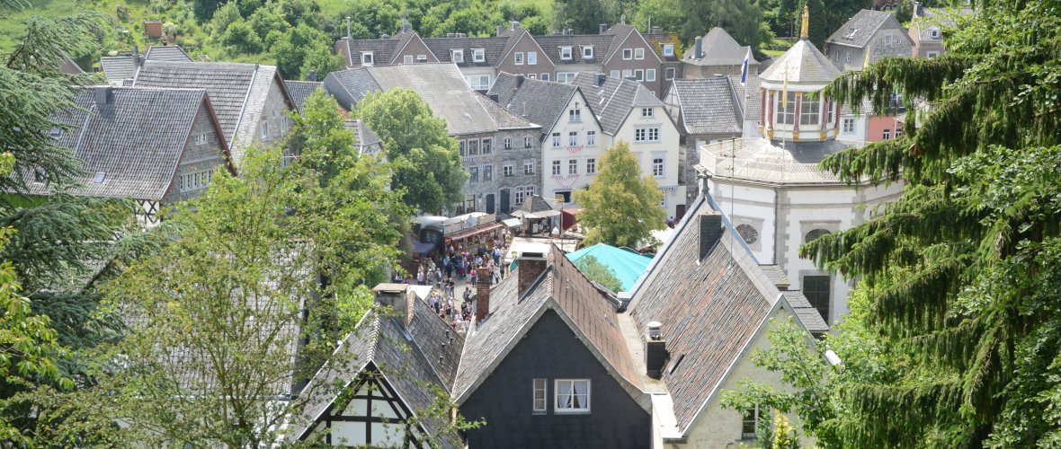 Der Ortskern von Kornelimünster zwischen grünen Wäldern und Wiesen - fotografiert von einem Hügel aus. Im Ort findet ein Volksfest statt.