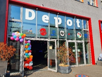 Eingangstür zum Depot mit bunten Luftballons und der Fensterbeklebung DEPOT.