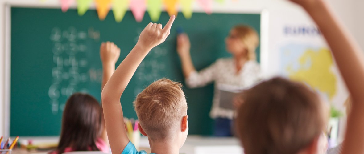 Kinder in einer schule, die Finger hben um drangenommen zu werden.