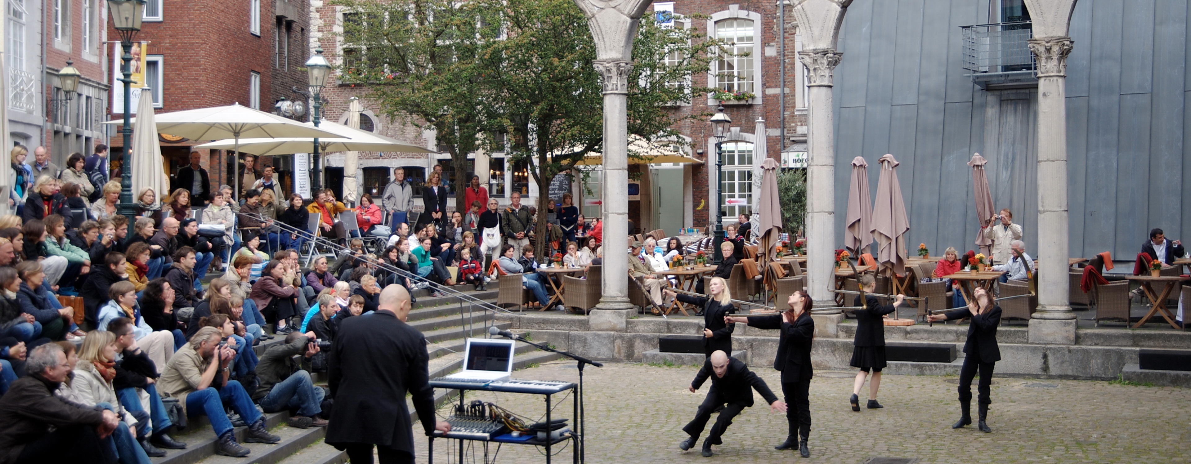 Der Hof in Aachen: Menschen performen Kunst, auf den Stufen drumherum sitzt viel Publikum
