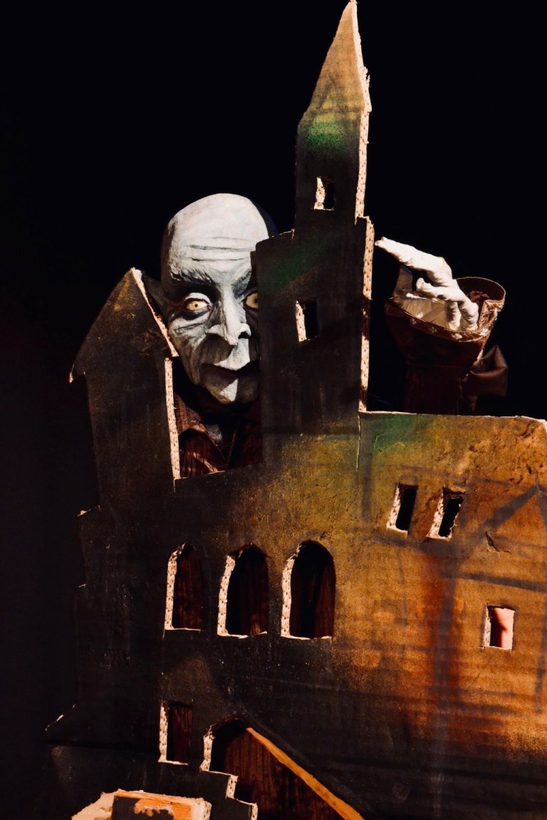 Eine Draculapuppe schaut hinter einem Turm hervor