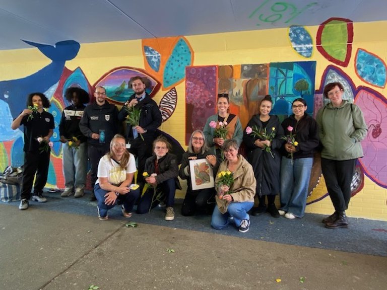 Eine Gruppe Menschen vor einer bemalten Wand in einer Unterführung.