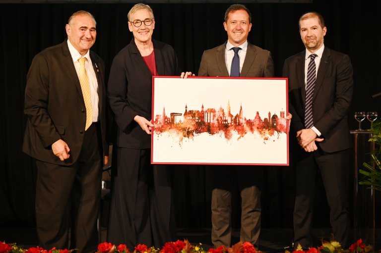 Vier Personen halten ein Bild fest