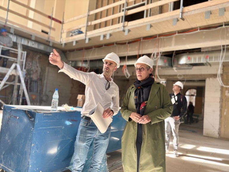 Ein Mann und eine Frau, die Oberbürgermeisterin, stehen im großen Saal des Neuen Kurhauses. Der Mann erläutert die Baustelle.