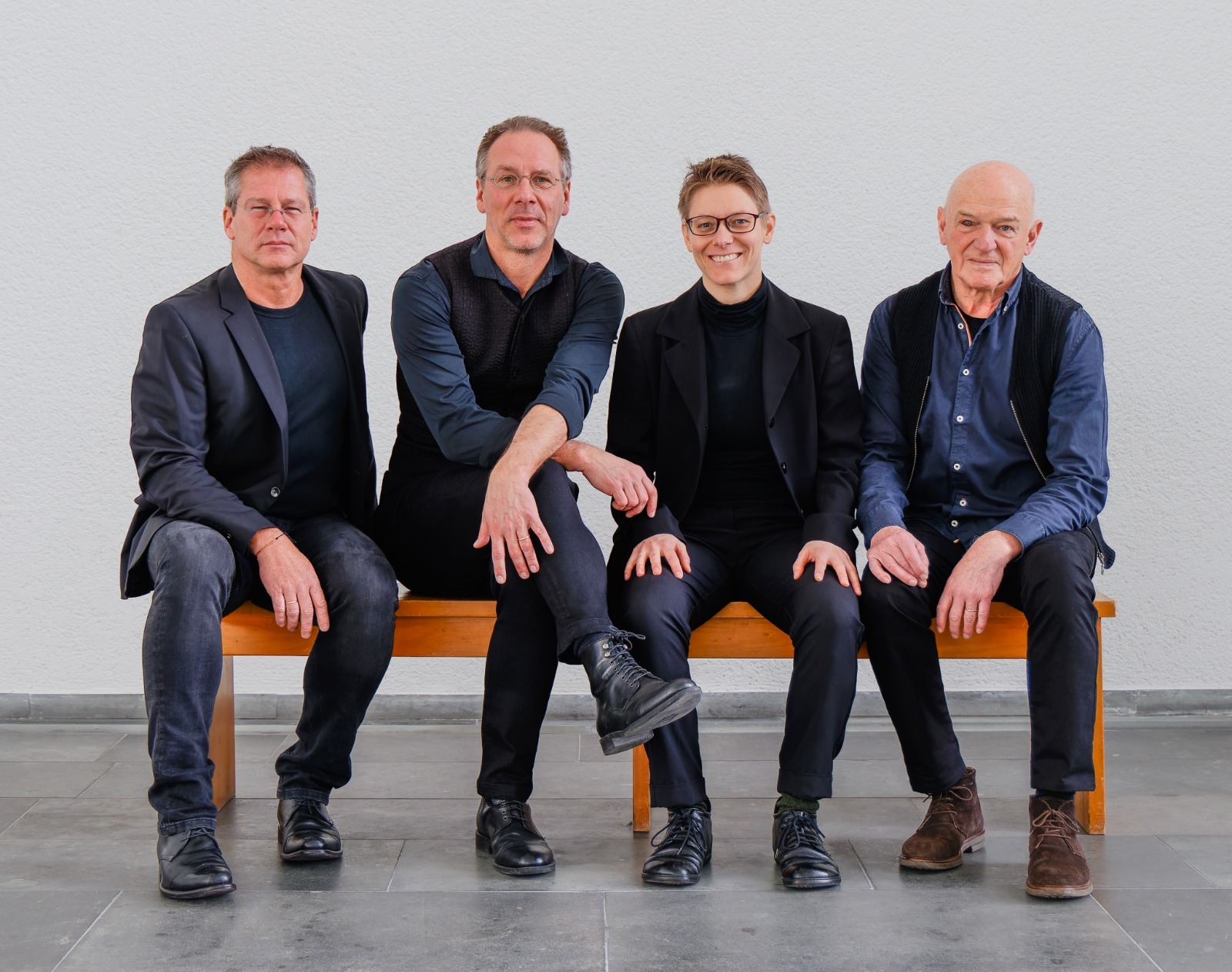 Vier Musiker des Christoph Leuchter Quartett nebeneinander auf einer Bank sitzend.