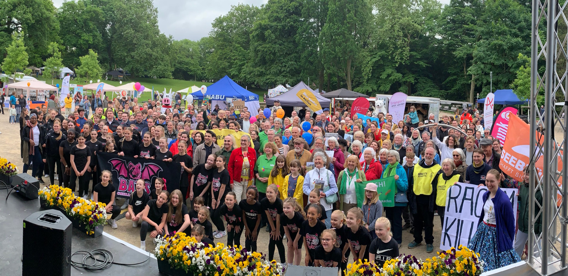 Eine große Gruppe Menschen steht vor einer Bühne.