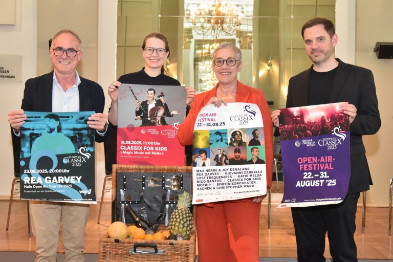 Vier Menschen mit Konzertplakaten und einem Picknickkorb.