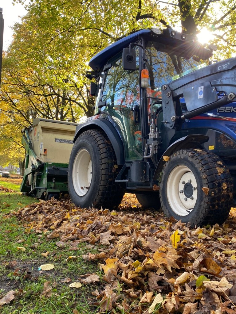Ein Traktor fährt über angehäuftes Laub an der Monheimsallee.